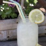 Two Brazilian jars of lemonade with straws on a wooden table.