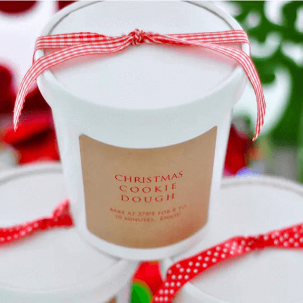 Simple, handmade Christmas cookie dough cups with red ribbons, perfect as gifts.