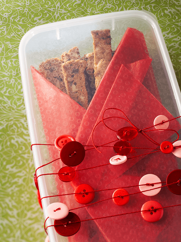 Handmade gifts of red and white marshmallows packaged in simple, clear bags on a pink background.