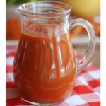 A pitcher of BBQ sauce on a table.