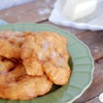 Fried Swiss Days scones on a plate with butter and syrup.