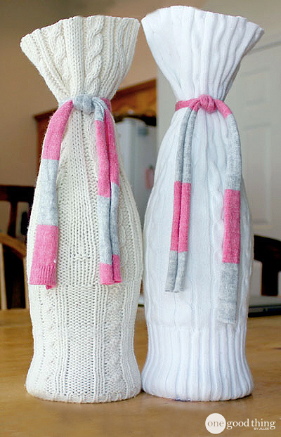 Two bottles covered with sweater sleeves and tied with knit strips