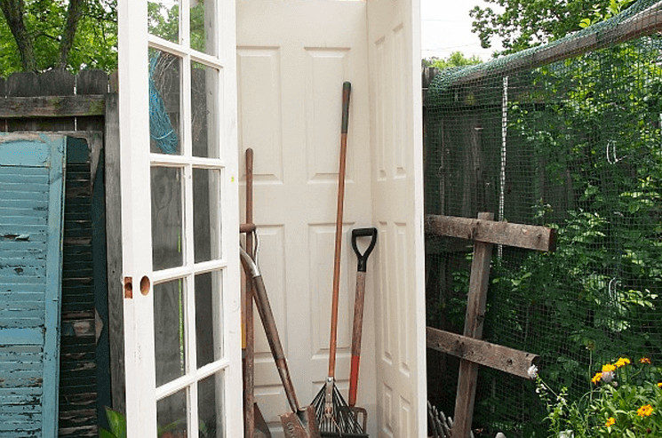 In a backyard, a garden shed welcomes visitors with its door open, revealing an array of tools and creating the perfect hangout spot for brainstorming genius ideas.