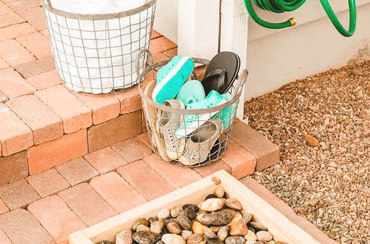 A backyard hangout spot featuring a wooden box filled with rocks and complemented by a nearby hose.