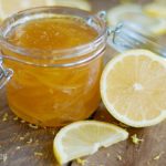 A homemade jar of lemon jam on a rustic wooden table.