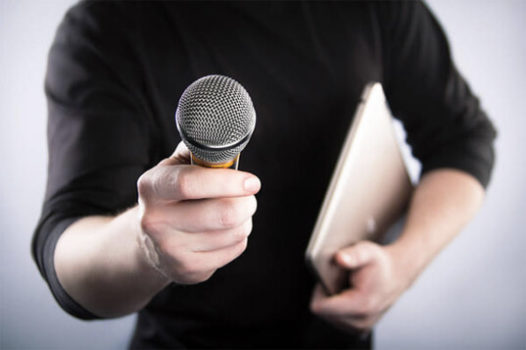A man holding a microphone in front of a laptop while conducting a Life Story Interview.