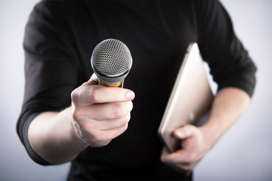 A man holding a microphone in front of a laptop while conducting a Life Story Interview.