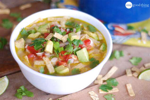 A bowl of Cafe Rio's chicken tortilla soup with tortilla chips and limes.