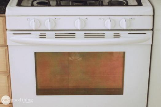 A wood oven in a kitchen with white cabinets.
