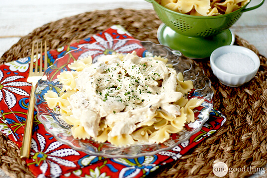 A creamy plate of pasta with chicken on it.