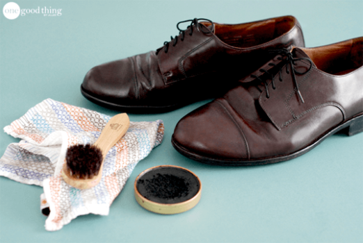 A pair of leather shoes next to a brush and a cloth.