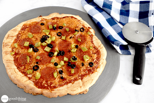 A gluten free pizza with pepperoni and olives on a plate.