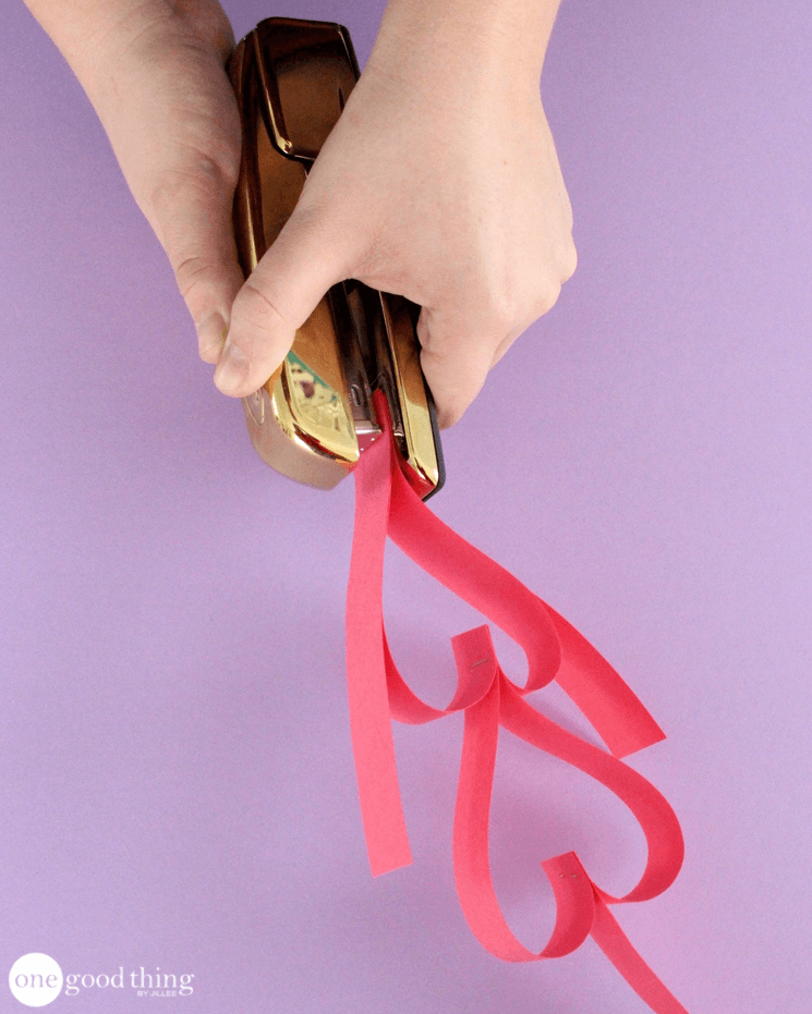 Adding a second heart to the paper heart chain with a stapler