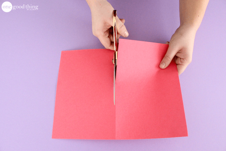 Cutting a sheet of red cardstock in half with scissors