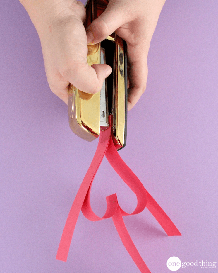 Stapling paper strips together at the point to form the first heart