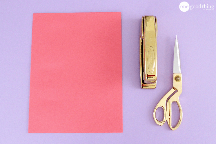 Supplies for paper heart chains: a sheet of red cardstock, a stapler, and scissors