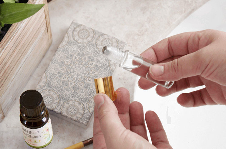 A person is holding a bottle of essential oil on a counter, offering headache remedies.