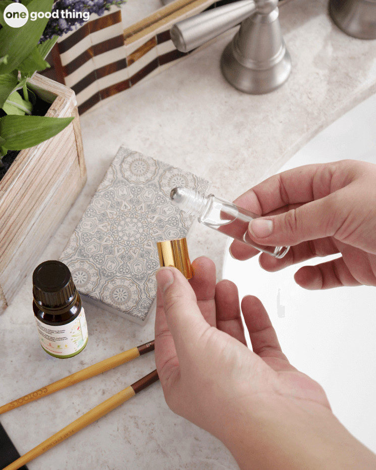 A person is holding a bottle of essential oil on a counter, offering headache remedies.