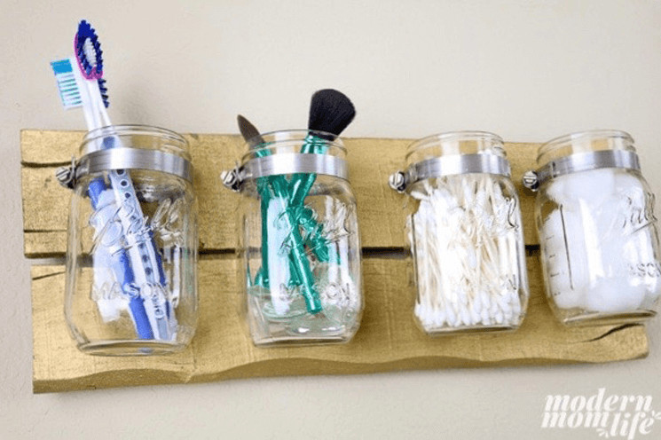 mason jar organizer set holding toothbrushes, makeup brushes, q-tips, and cotton balls