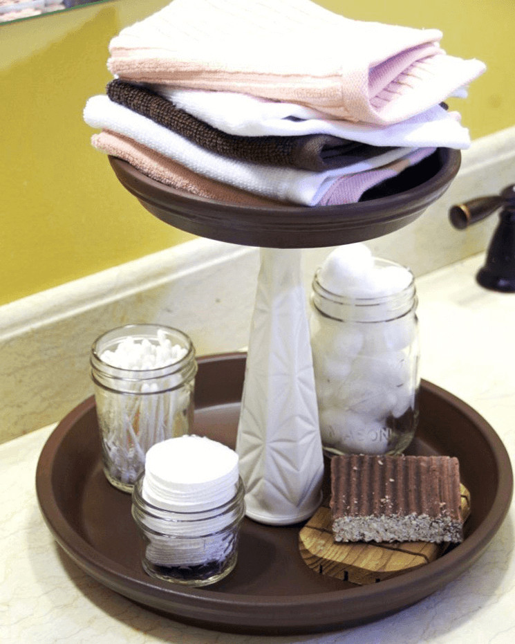 mason jars holding q-tips, cotton balls, and cotton rounds sitting on a tiered organizer holding towels on a bathroom counter