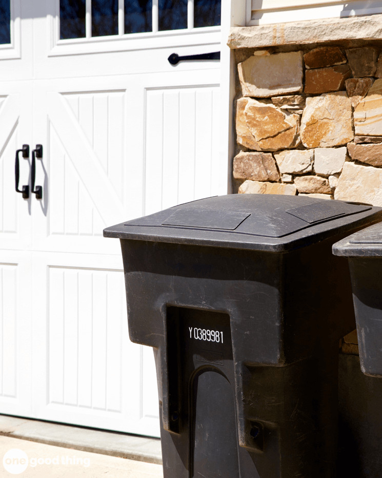 black garbage cans sitting in front of a house 