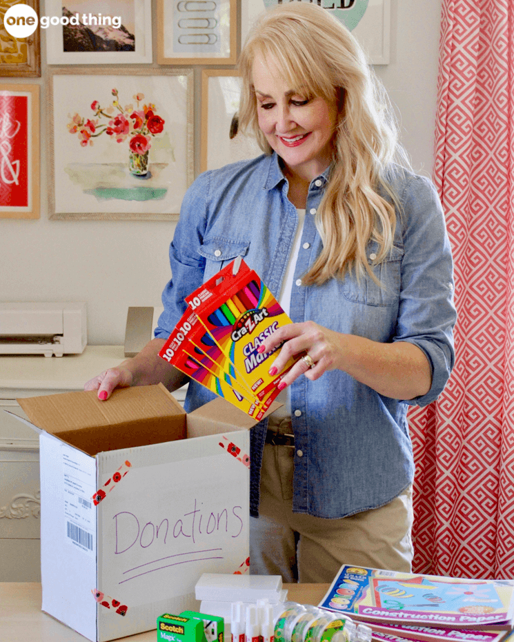 woman putting boxes of markers into a donation box