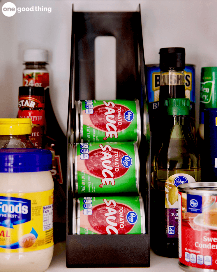 cans of tomato sauce organized in a cabinet shelf with various other food sitting around 