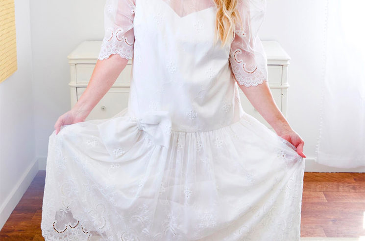 A blonde woman in a wedding dress posing in a room.