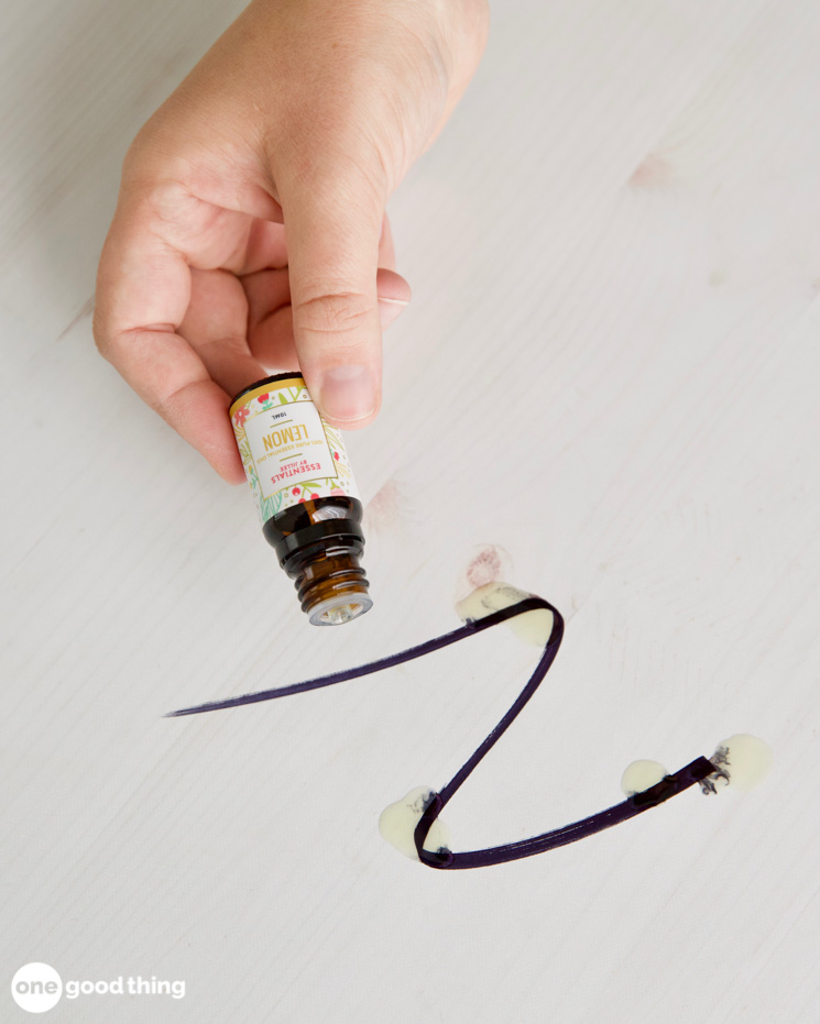 cleaning with essential oils - lemon essential oil being sprinkled on magic marker stain on a surface