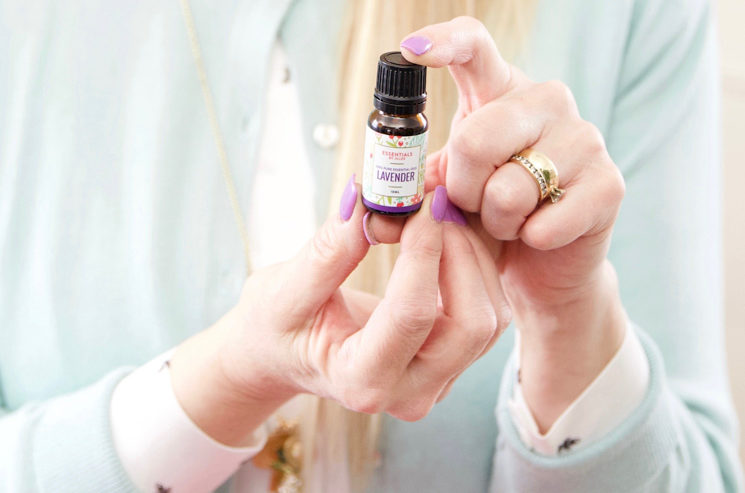 A woman holding a bottle of essential oil for everyday aches relief.