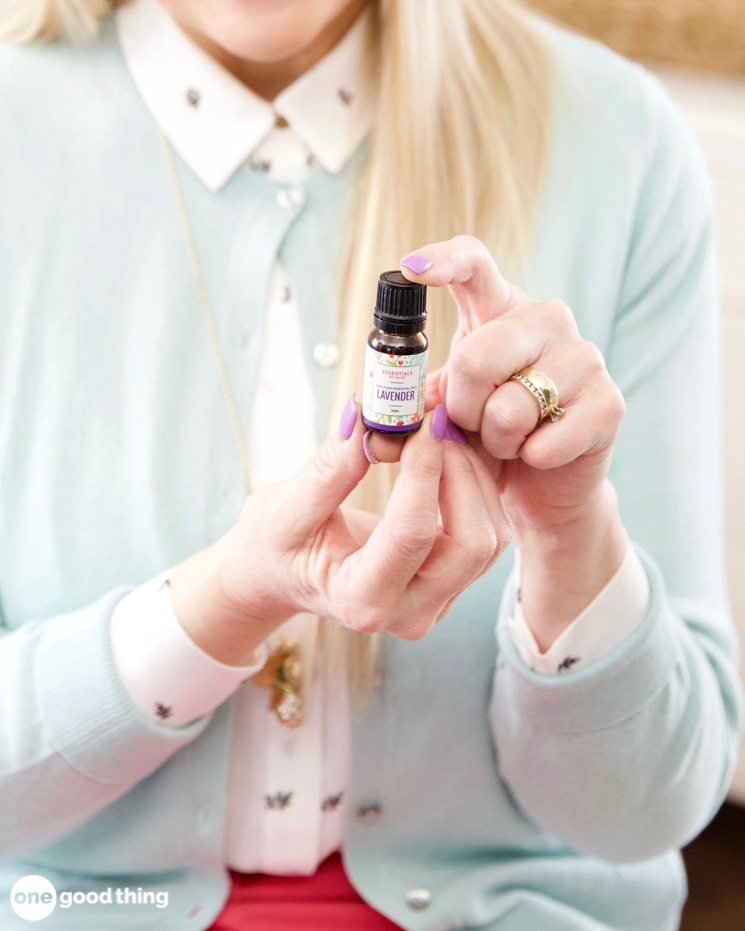 A woman holding a bottle of essential oil for everyday aches relief.