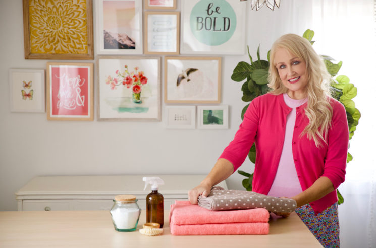 A woman is putting towels on a table, showcasing Just One Good Thing.
