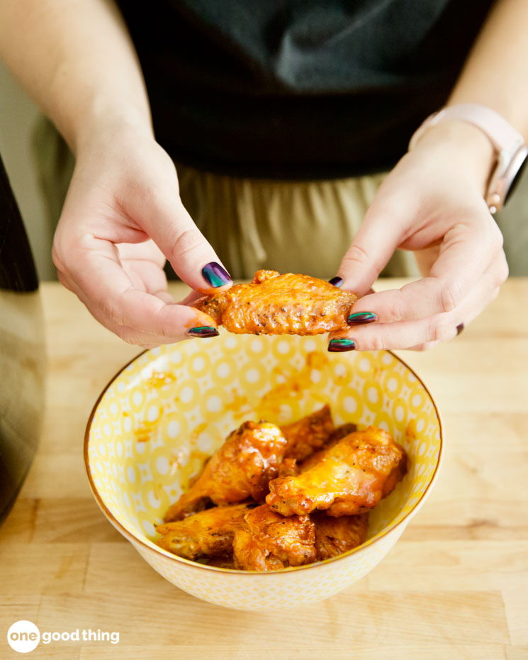 woman's hands holding up a chicken wing