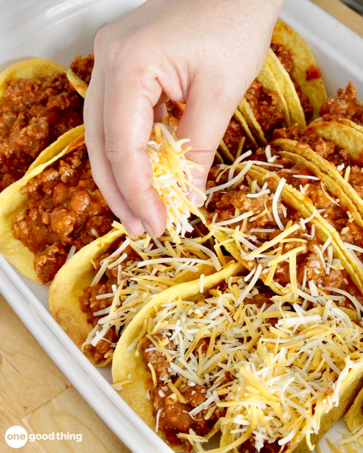 Top the filled taco shells with shredded cheese.
