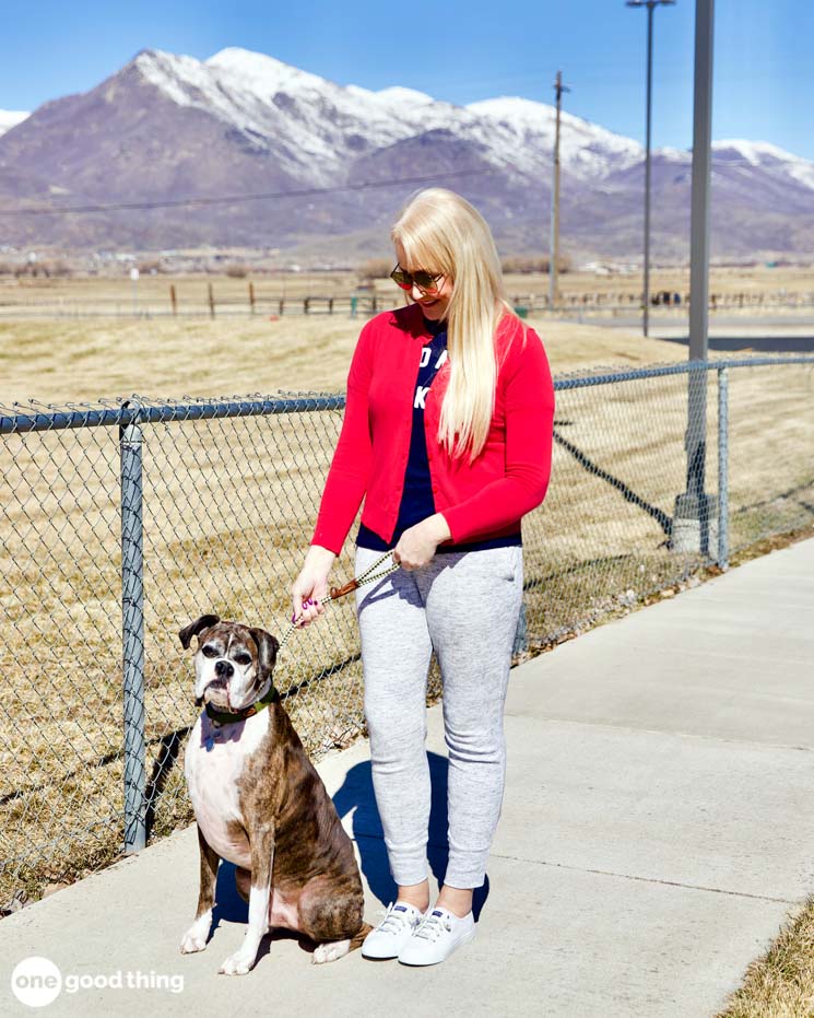 woman walking a dog outside with mountains in the background
