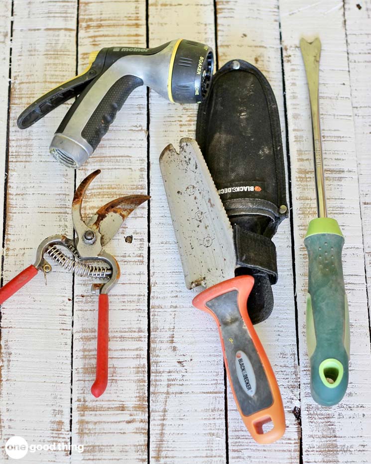 assortment of gardening hand tools on rough white boards
