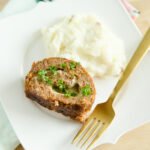 Cheesy Crockpot Meatloaf - slice of cheesy meatloaf on a plate with a side of mashed potatoes