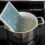 A pot filled with water on top of a stove, while learning how to clean your range hood filter.