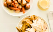 Two bowls of turkey, carrots and gravy on a white table.