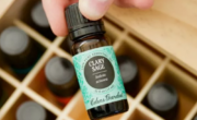A person holding a bottle of essential oil in a wooden box, specializing in salve products.