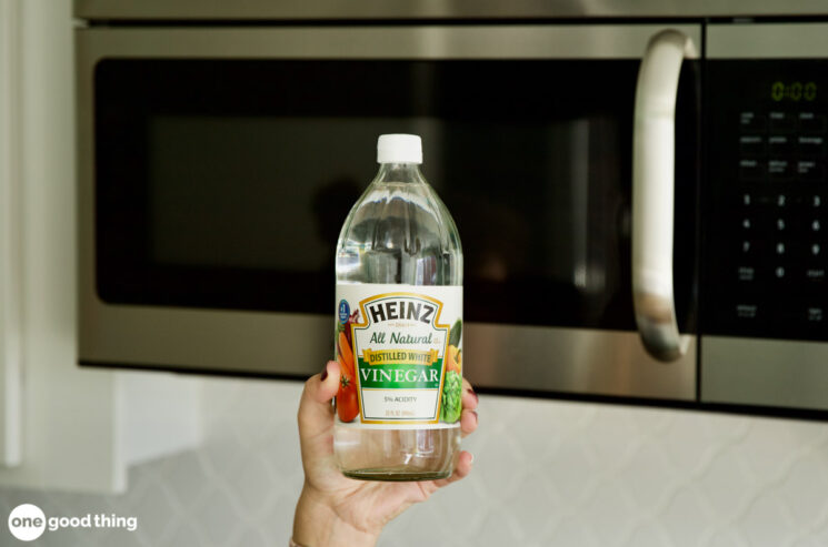 A person holding a bottle of distilled white vinegar