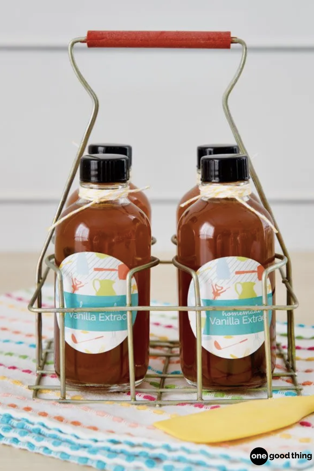Three bottles of vanilla extract syrup in a metal basket on a table.