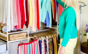 A woman standing in front of a closet full of clothes, contemplating which things to get rid of.