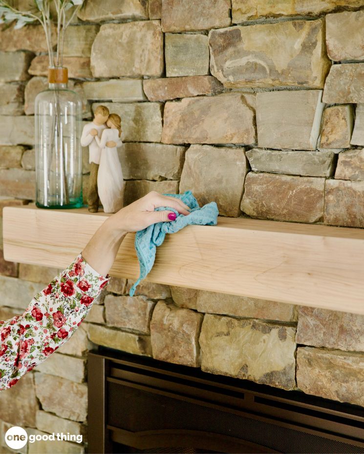 A person cleaning a fireplace with microfiber cloths.