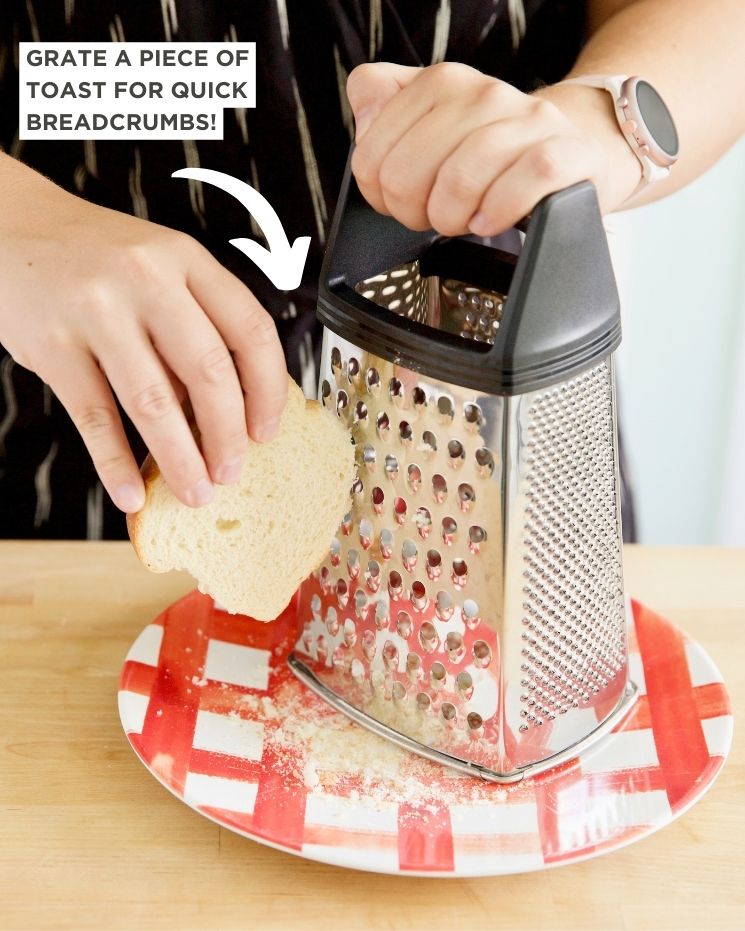 A person grates a piece of toast for breadcrumbs.