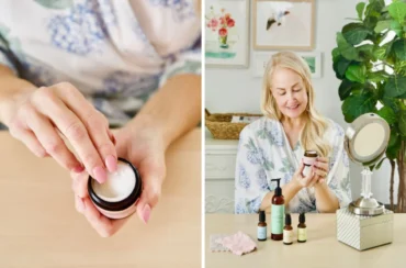 A woman in a floral robe applies the best moisturizer from a jar, with skincare products arranged on a vanity table in front of her.