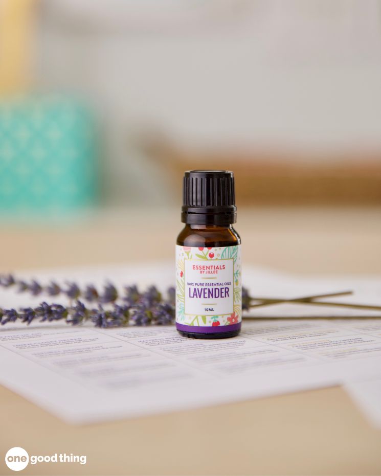 A small bottle of lavender essential oil sits on a table next to lavender sprigs and sheets of paper—perfect for soothing mosquito bites naturally.