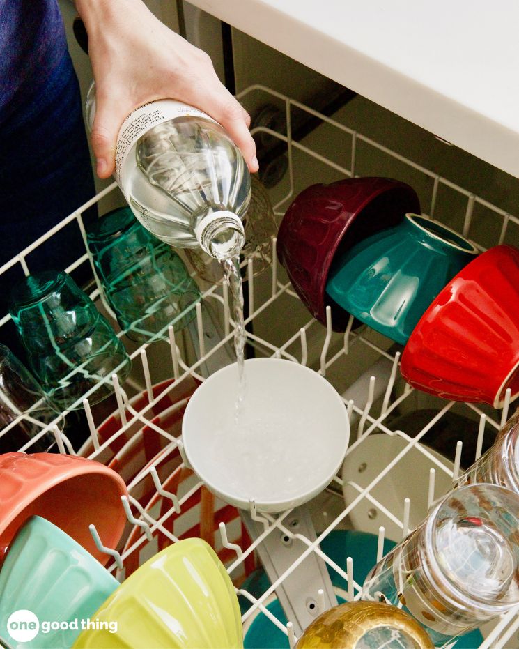 dishwashing hacks_1 A person pours clear dishwashing liquid from a bottle into a bowl placed on the top rack of a dishwasher filled with colorful dishes.