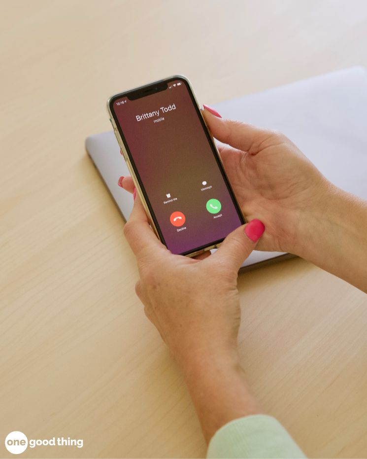 what to do if you're scammed_3 A person holding a smartphone with an incoming call from