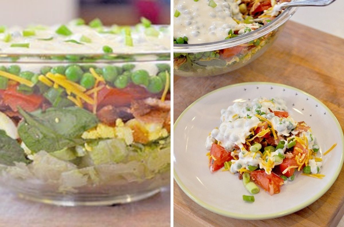 A retro salad masterpiece, this glass bowl layered dish features lettuce, spinach, bacon, eggs, peas, tomatoes, cheese, and dressing; a serving is plated beside the bowl on a small white plate.